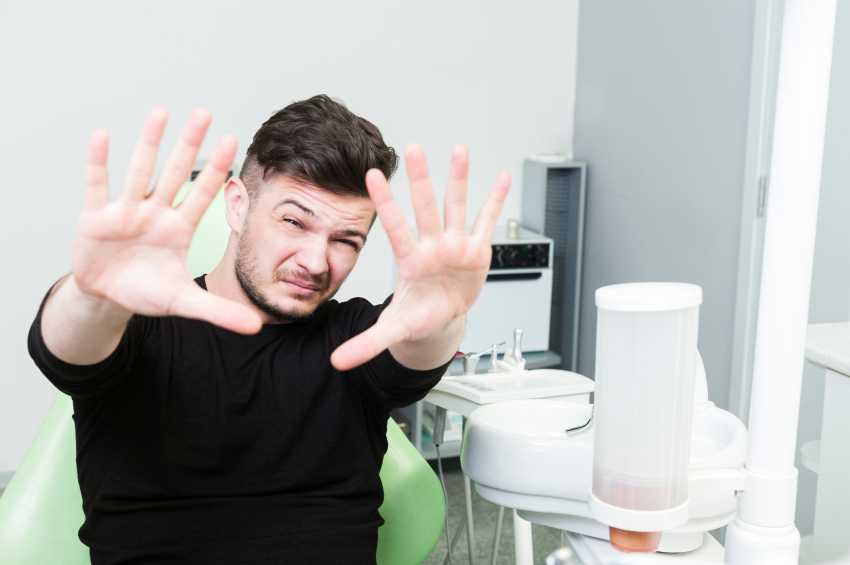 Handsome male patient acting scared in dentist office Zahnarztangst Sensitive Dentists